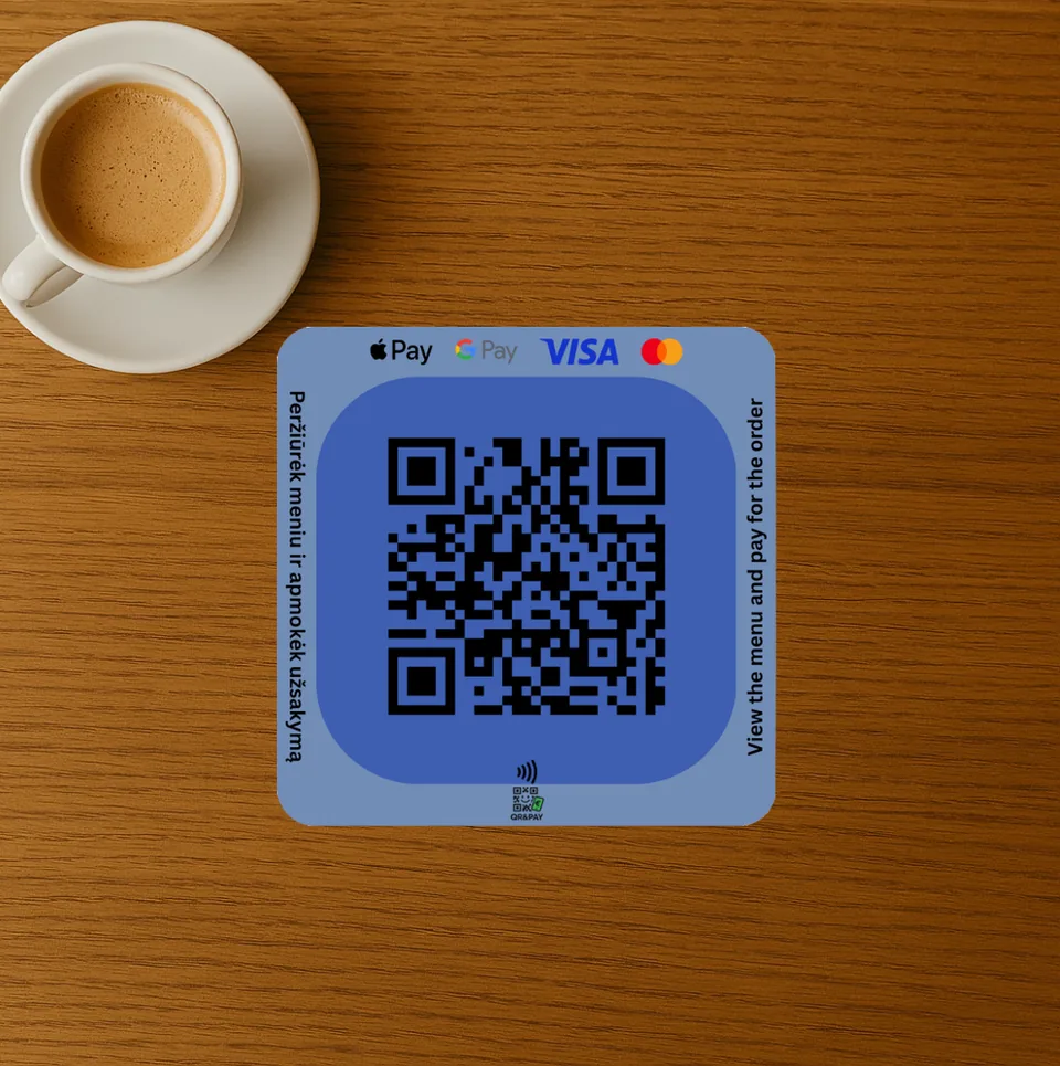 A QRandPay QR sticker on a cafe table next to a cup of coffee